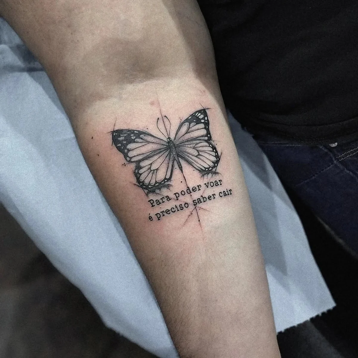 Mariposa y frase — tatuaje de Kozo en antebrazo